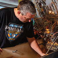 A man fixing an open pinball machine