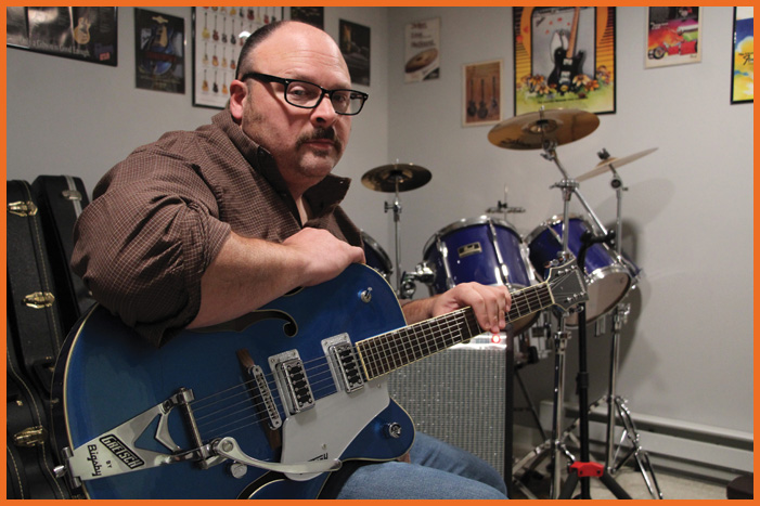 Image of a man holding a blue guitar