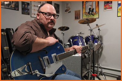 Image of a man holding a blue guitar